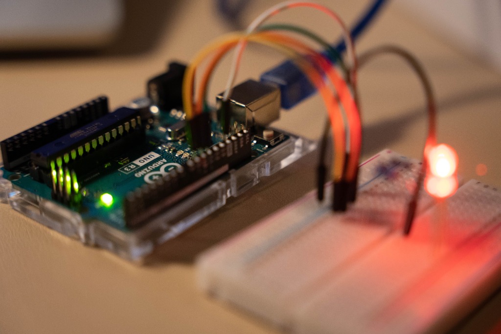 Placa Arduino UNO conectada a una protoboard con cables y un LED rojo encendido