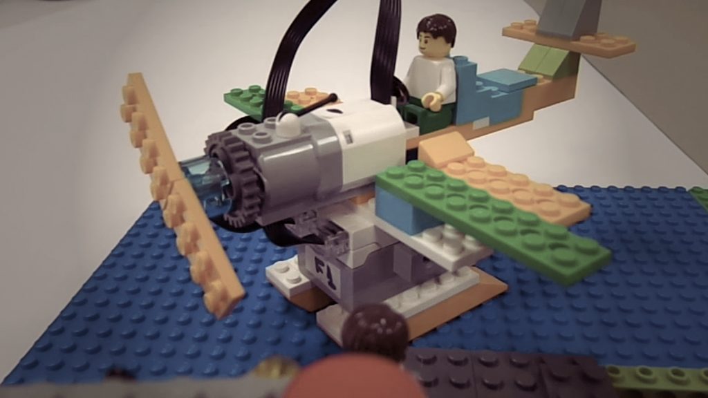 Avión construido con piezas LEGO y un motor, montado sobre una base azul