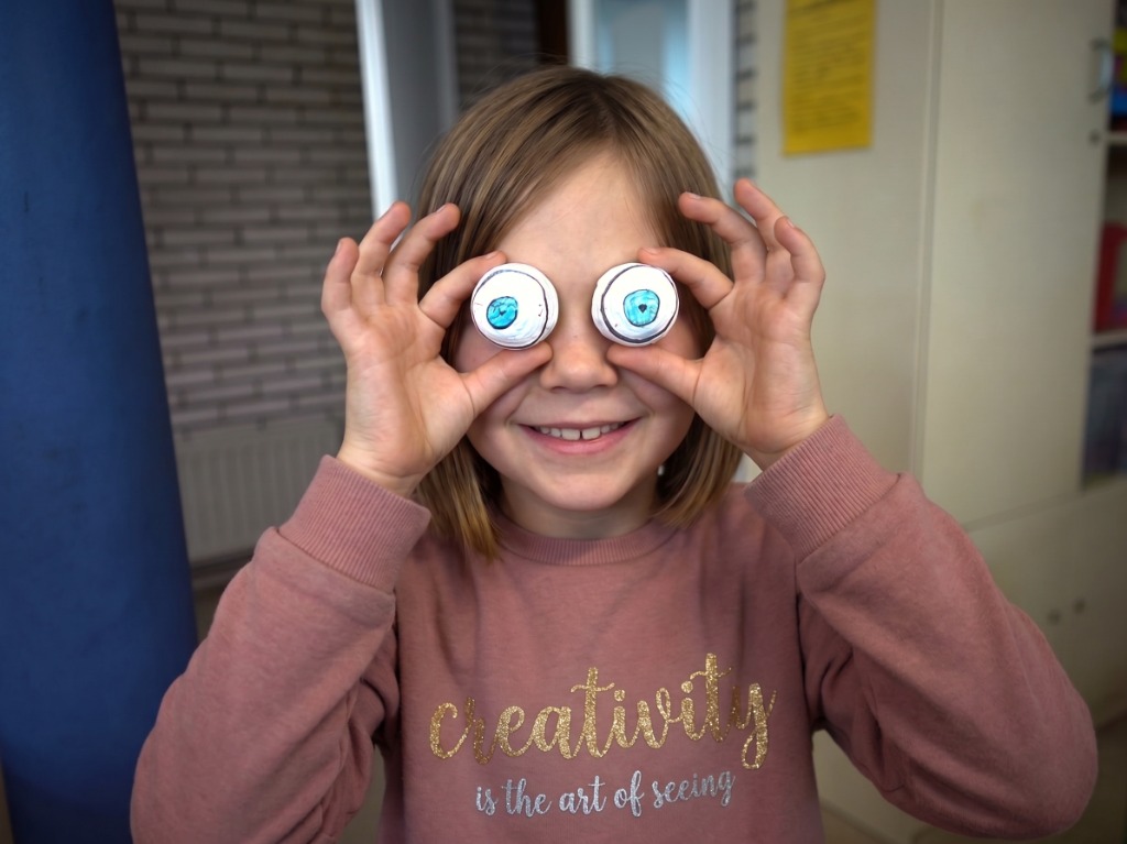 Una alumna mira a través de dos piezas circulares a modo de ojos