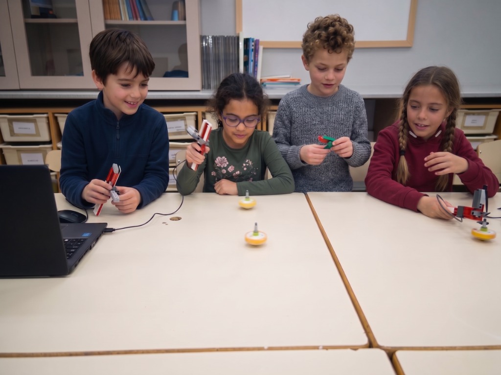 Cuatro alumnos haciendo girar peonzas robóticas LEGO en una mesa de taller