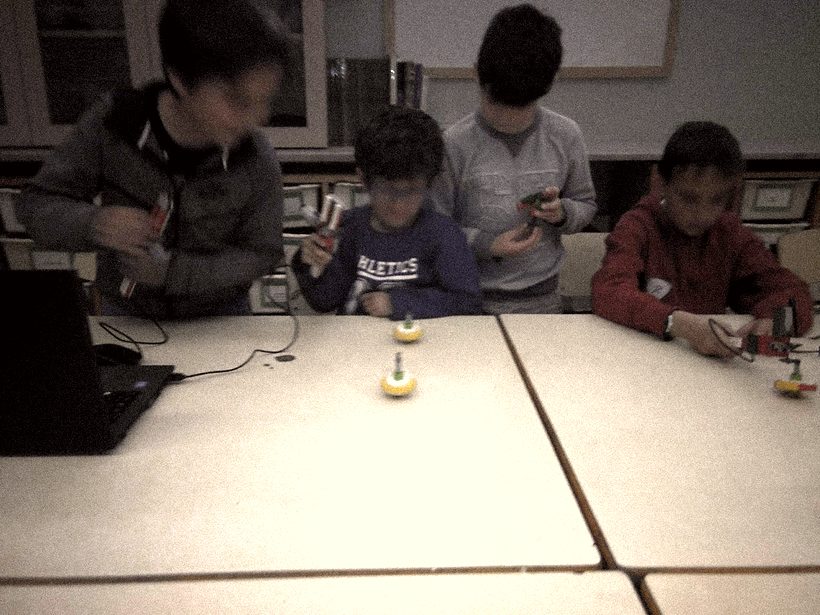 Cuatro alumnos montando robots en una mesa de taller
